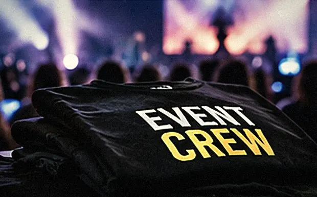 Gefaltete schwarze Event-Crew-Shirts vor einer Konzertbühne